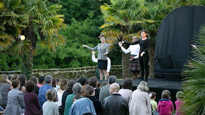Vue d'un spectacle sur scène dans un jardin avec public de dos au premier plan